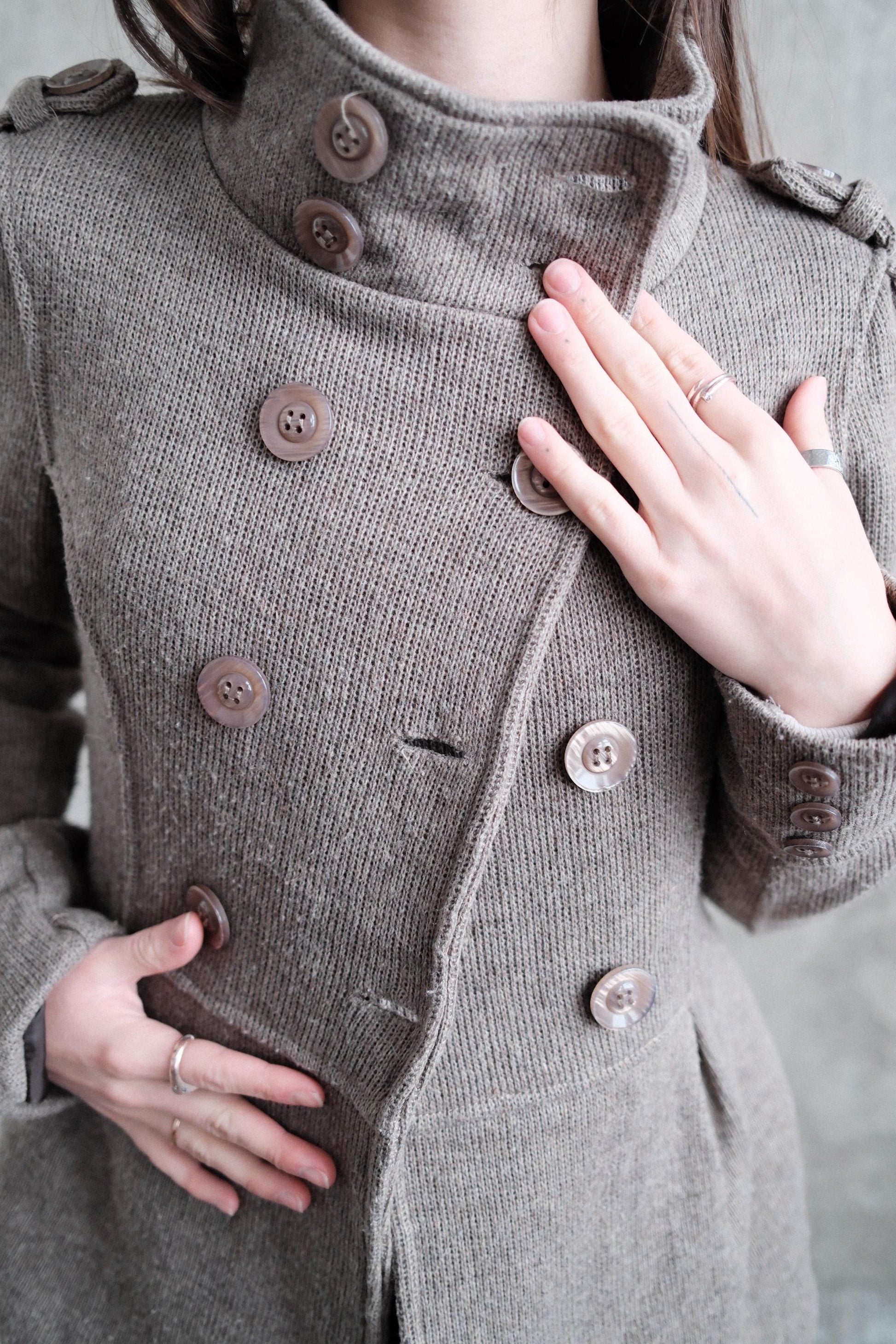 A close-up view of a person's torso wearing a gray double-breasted coat with buttons.
