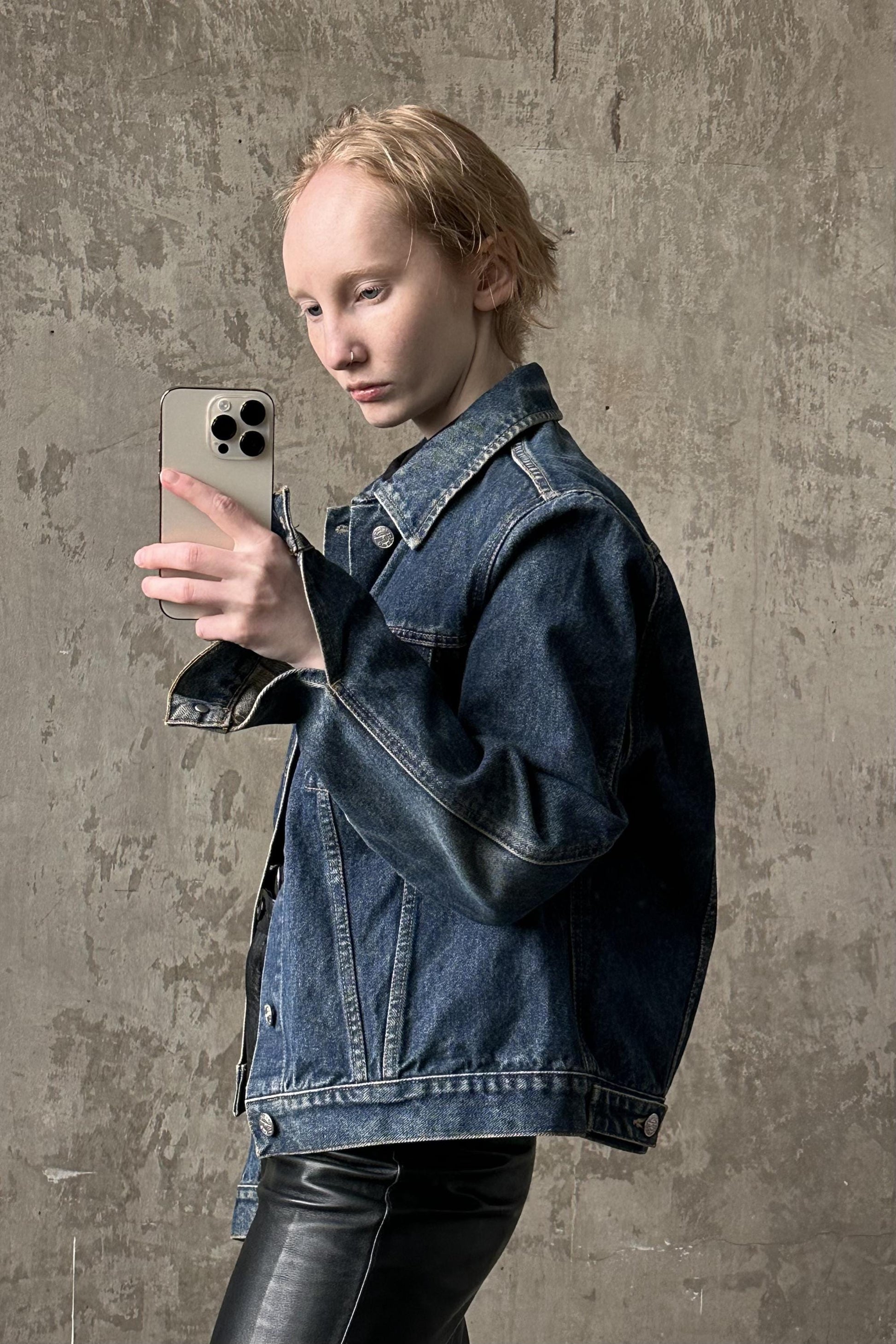 a woman in a denim jacket holding a cell phone