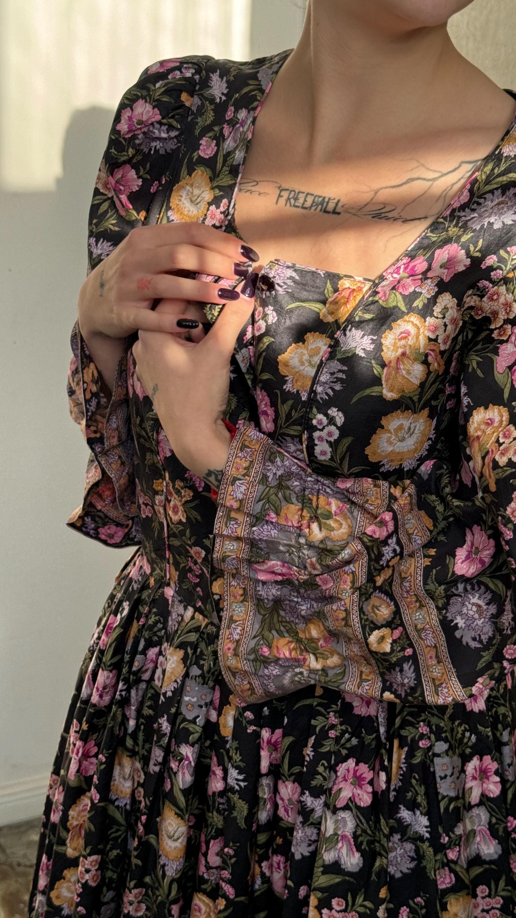 A woman wearing a floral print dress with a tattoo on her neck.