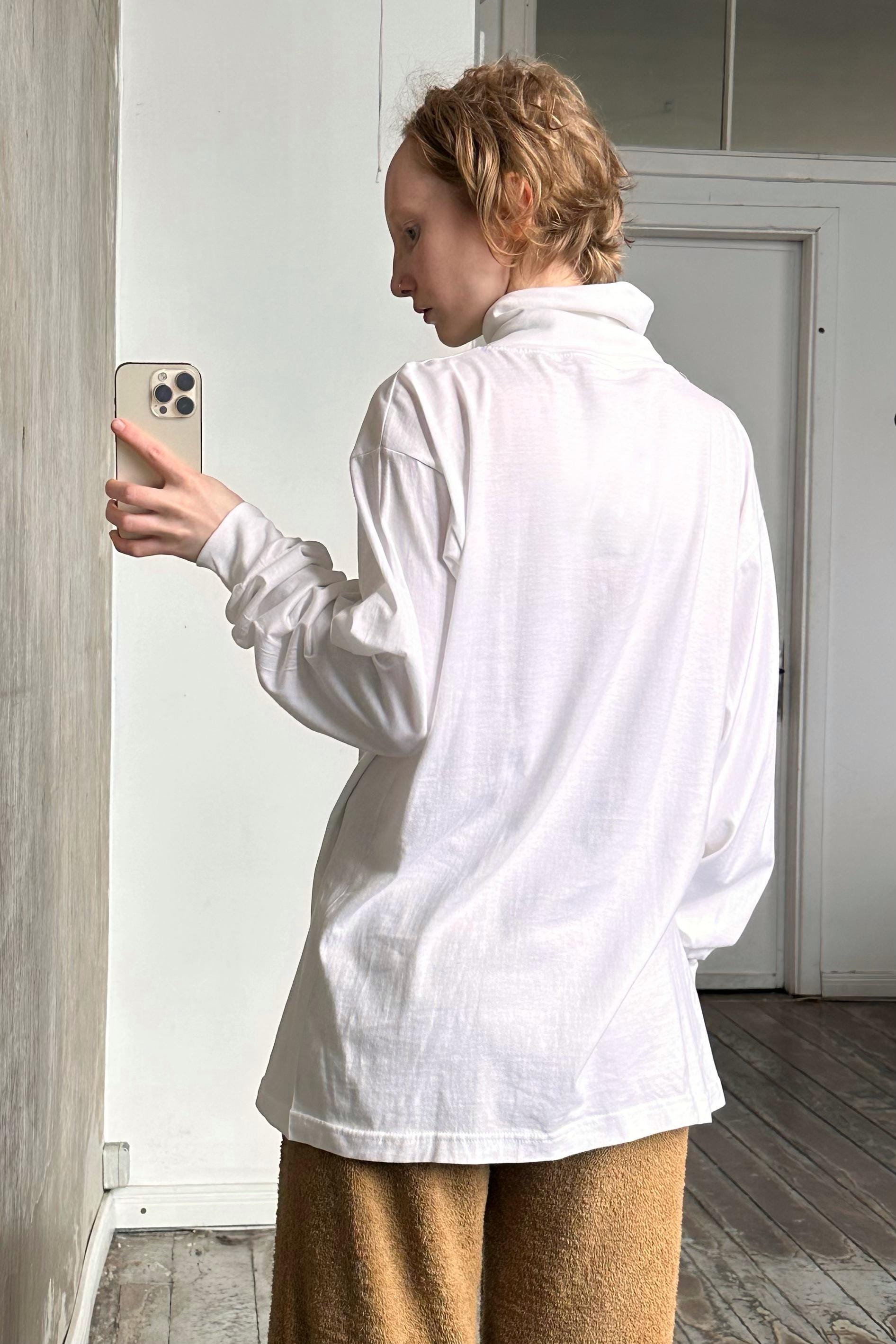 a woman in a white shirt is holding a cell phone