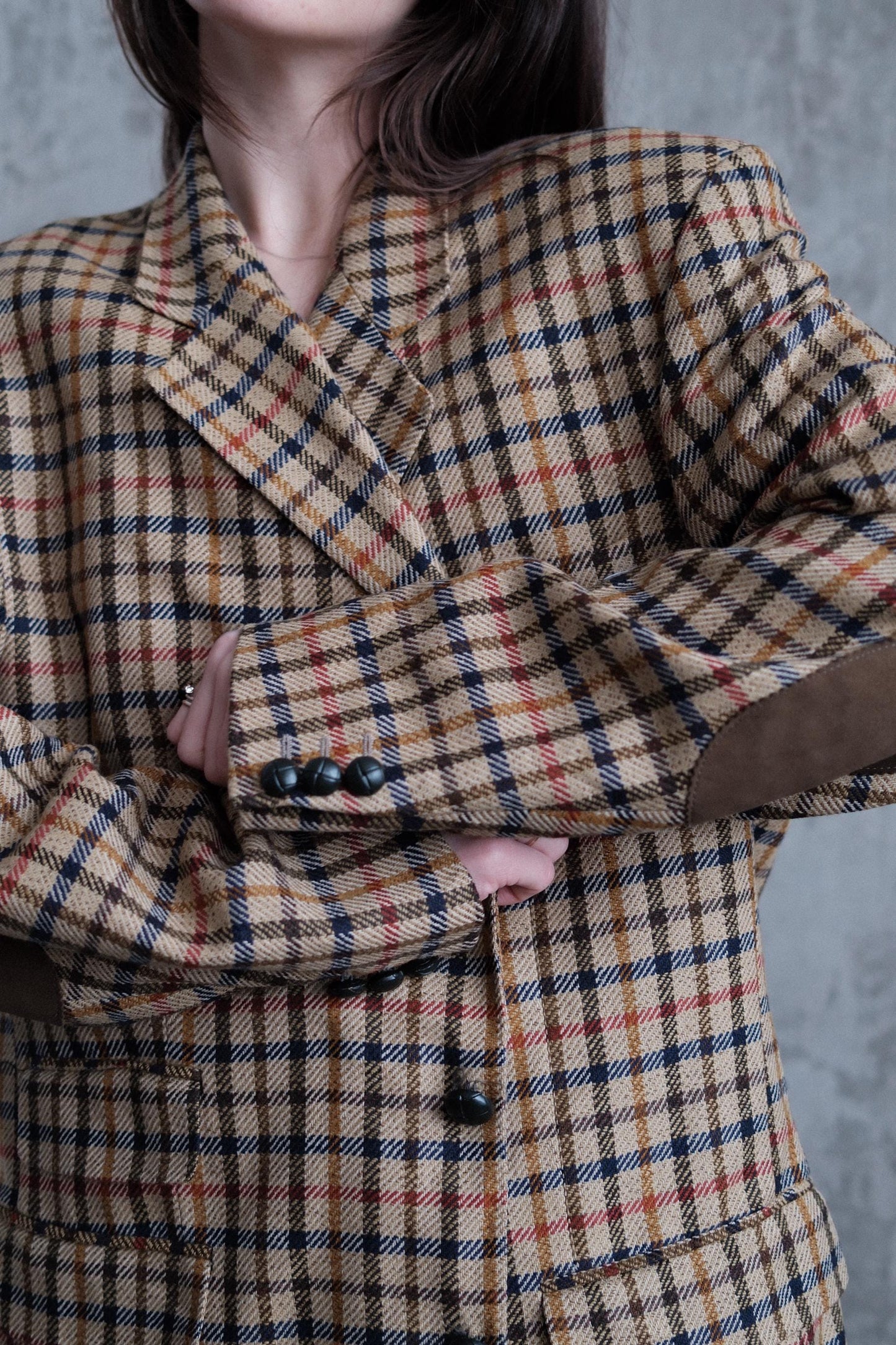 A close-up of a person wearing a plaid jacket with a pattern of red, black, and white stripes.