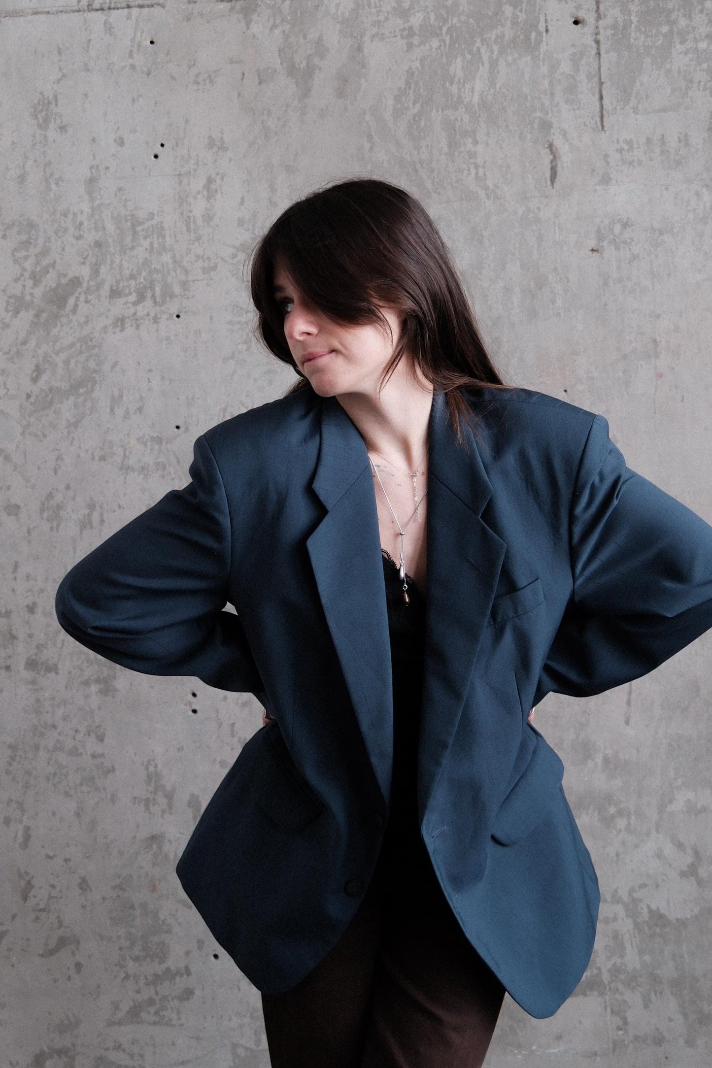 A woman in a blue blazer is captured in a dynamic pose against a plain gray background.