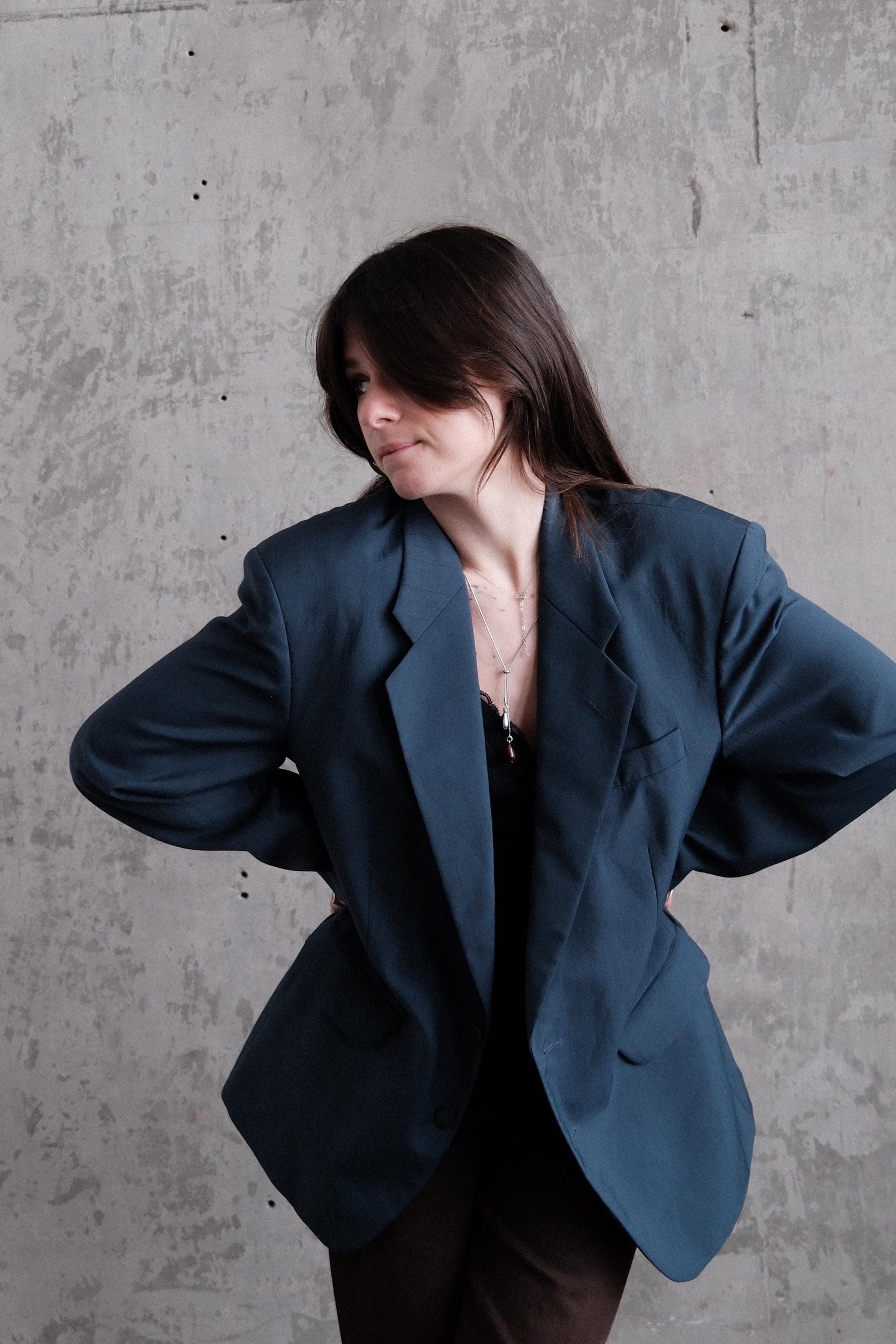 A woman in a blue blazer is captured in a dynamic pose against a plain gray background.