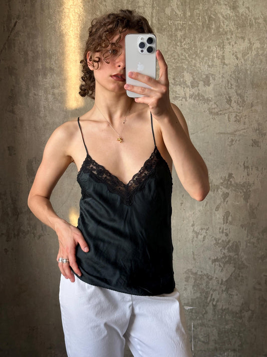 A woman is taking a selfie with her iPhone, holding the device up to her face to capture her image.
