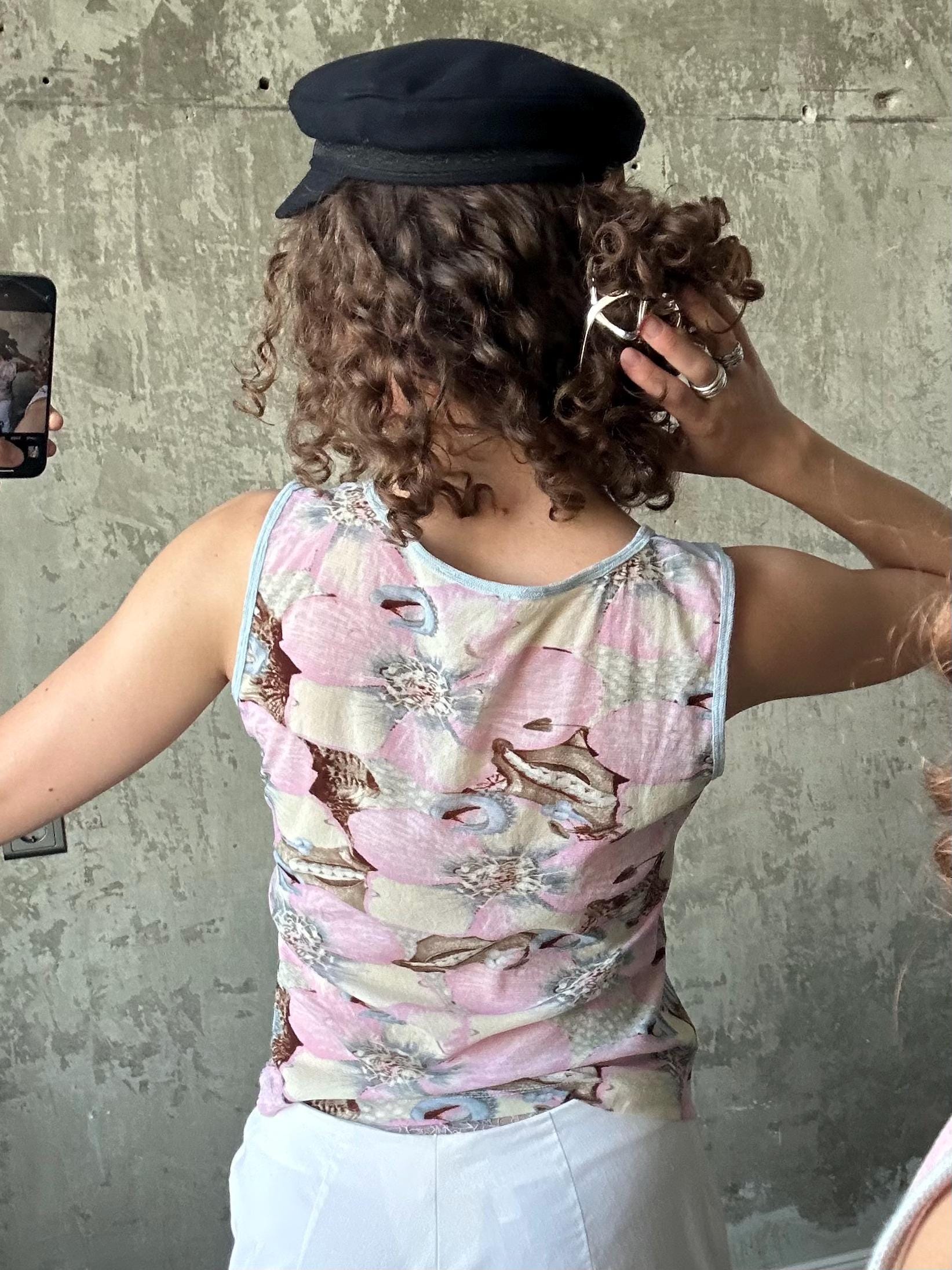 a person taking a selfie in front of a concrete wall, with their back facing the camera.