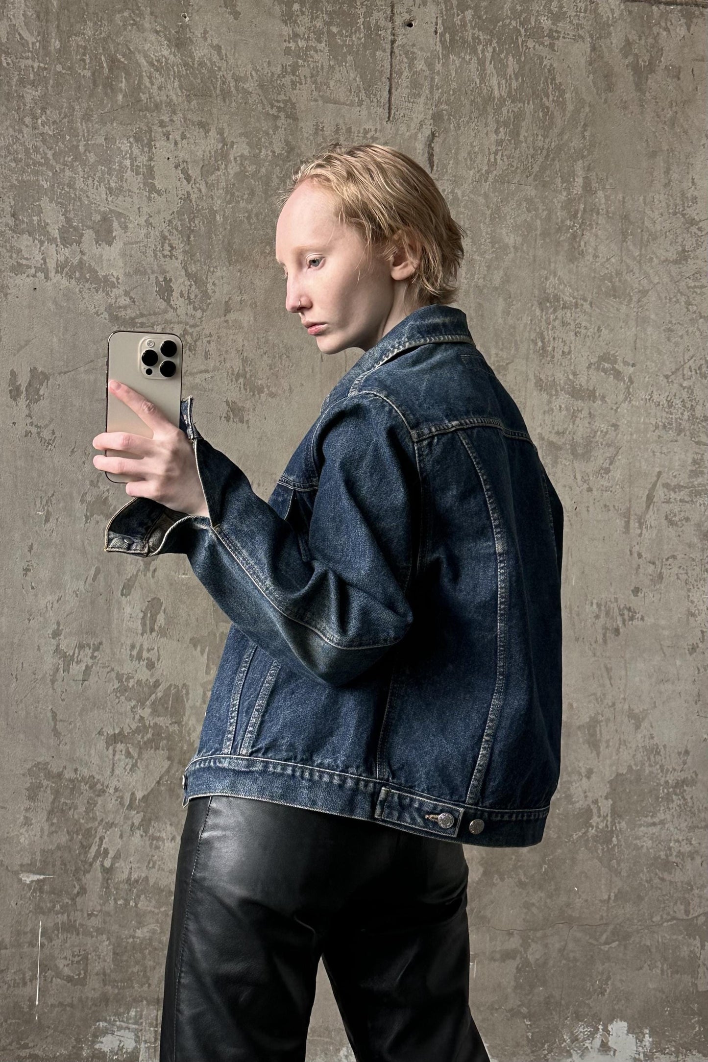 a woman in a denim jacket holding a cell phone