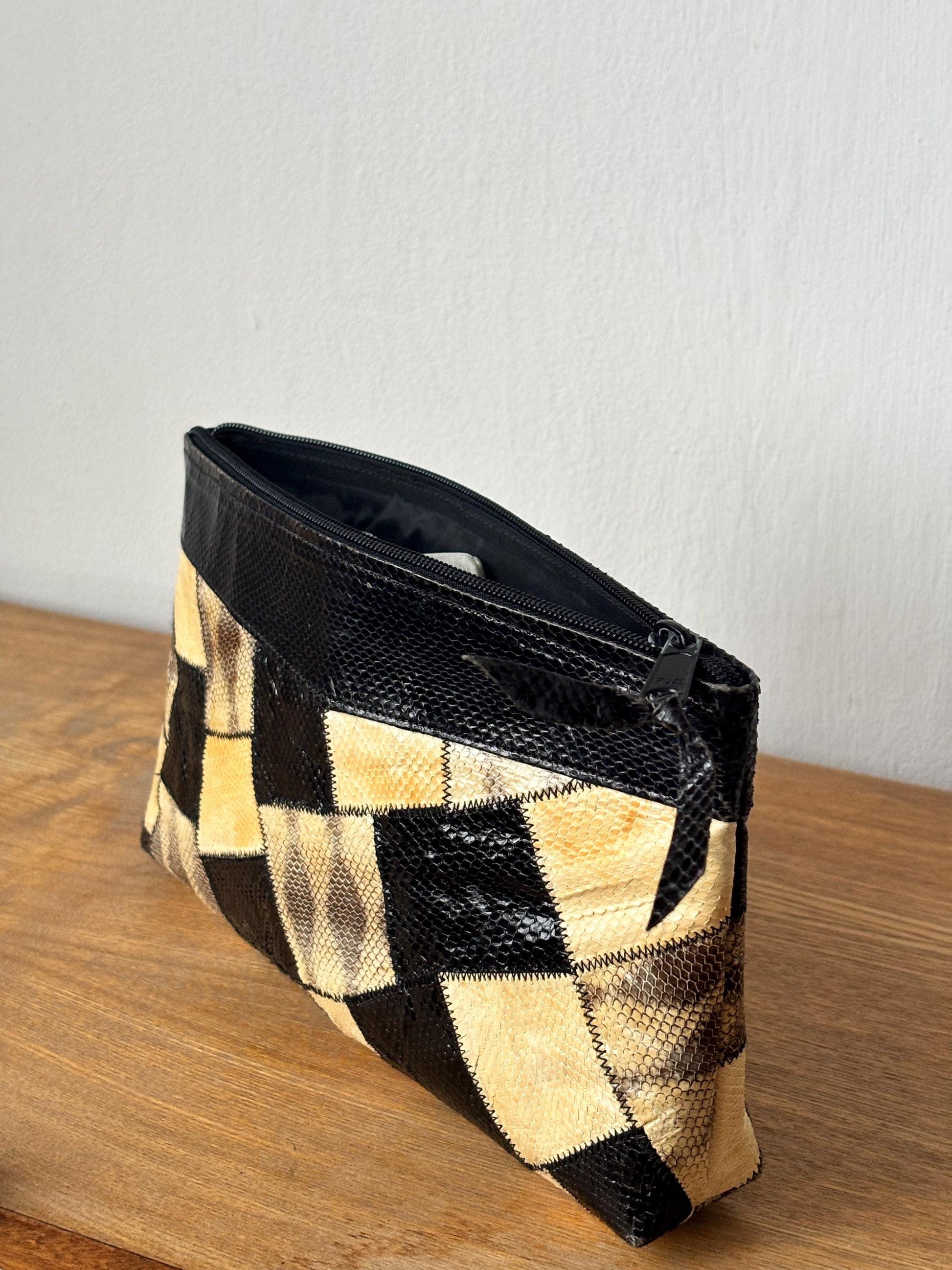 A black and white checkered patterned handbag with a zipper closure is sitting on a wooden surface.