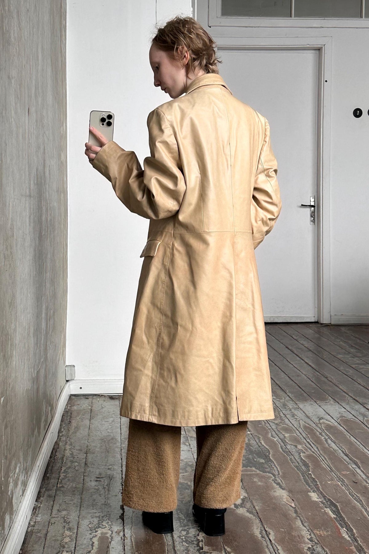 a woman standing in a room looking at her cell phone