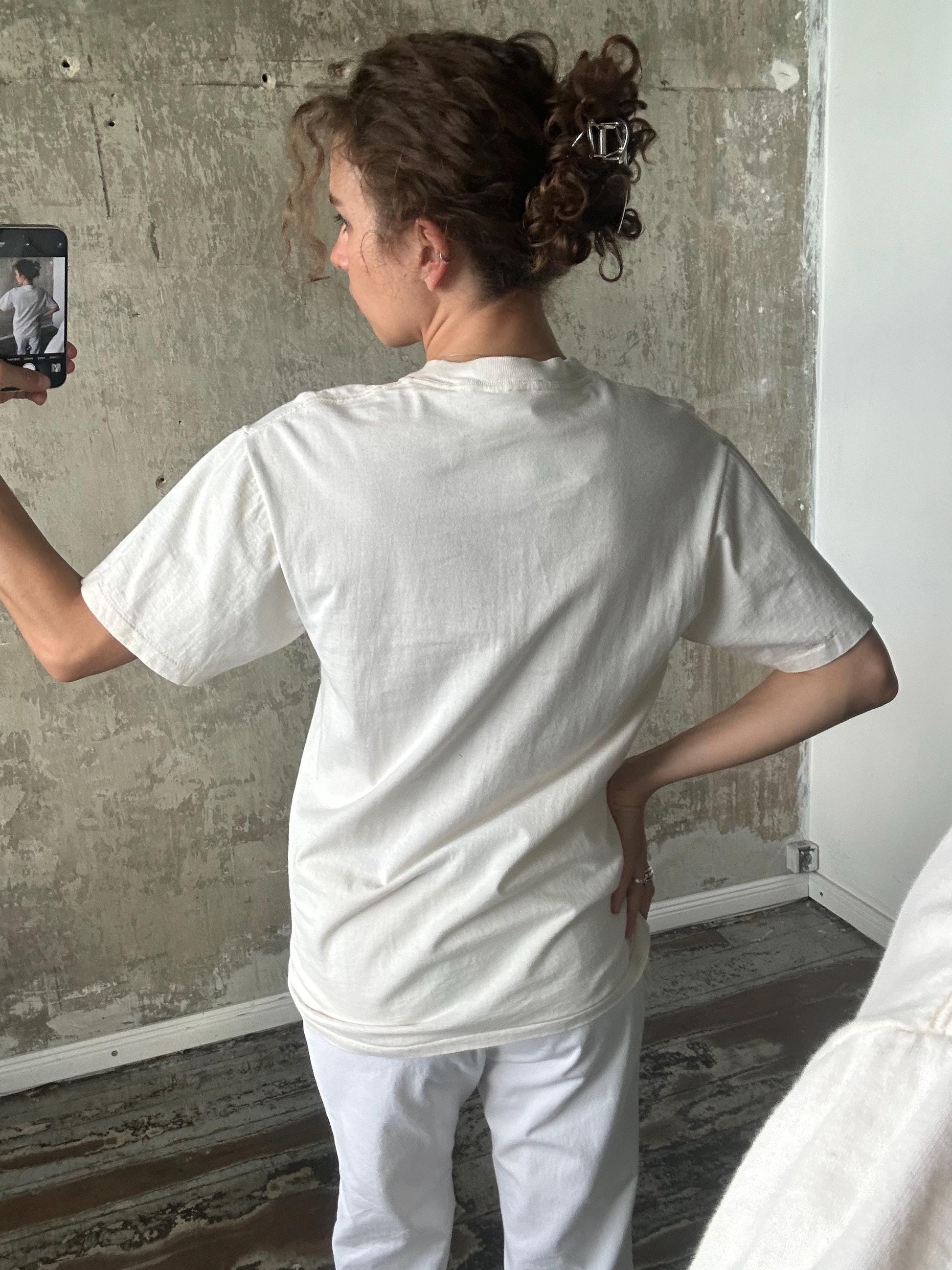 A person is taking a selfie with a smartphone, capturing their back view.