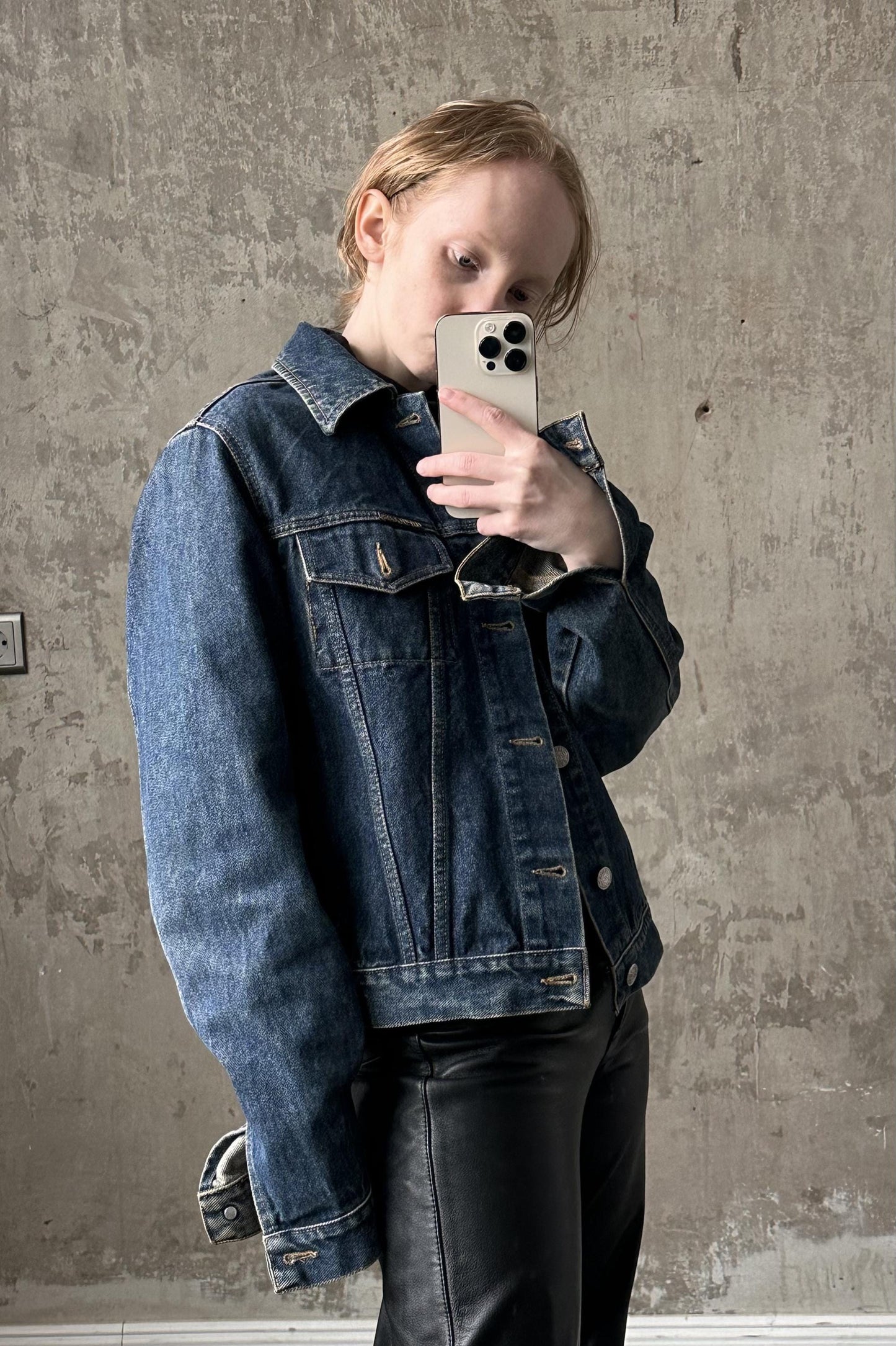 a woman in a denim jacket holding a cell phone