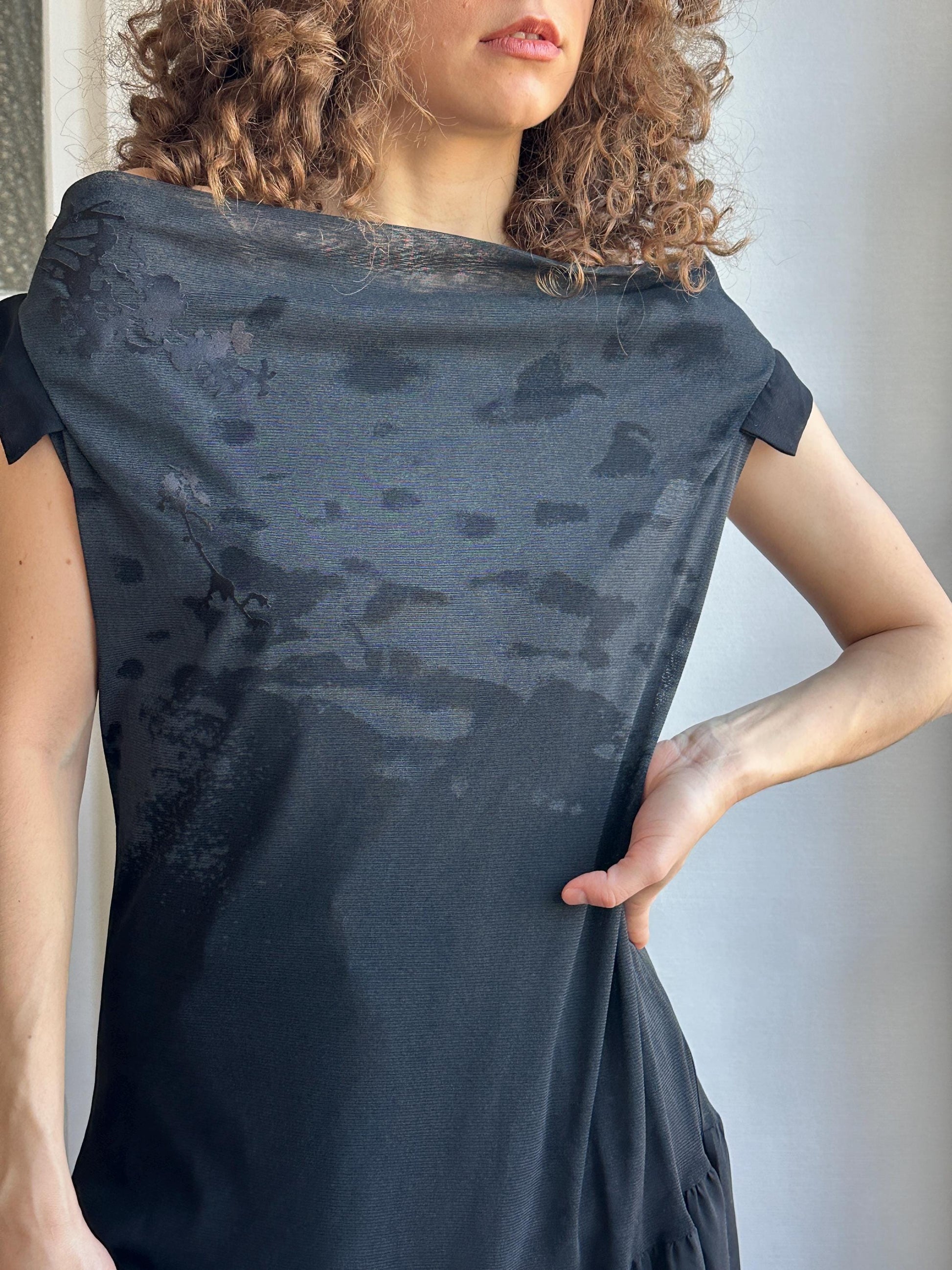 A close-up of a person's torso wearing a black dress with visible stains or marks on it.