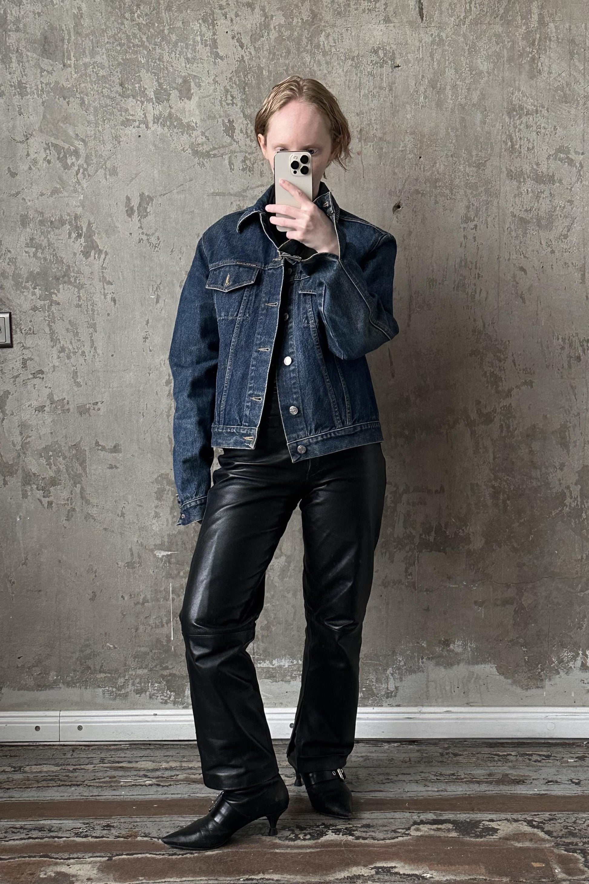 a woman in a denim jacket taking a selfie