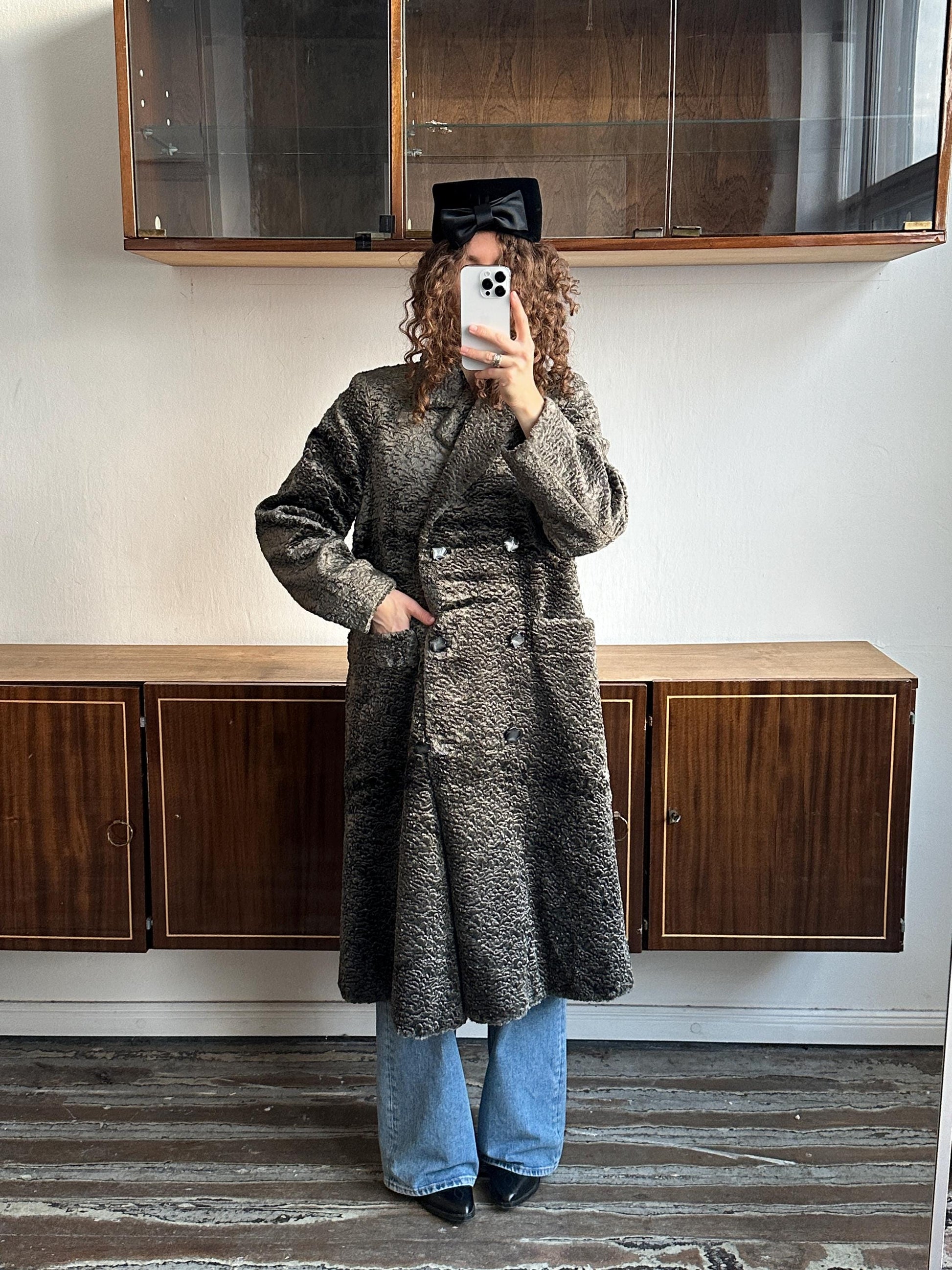 A person is taking a selfie in a room with wooden furniture, including a dresser and a cabinet.