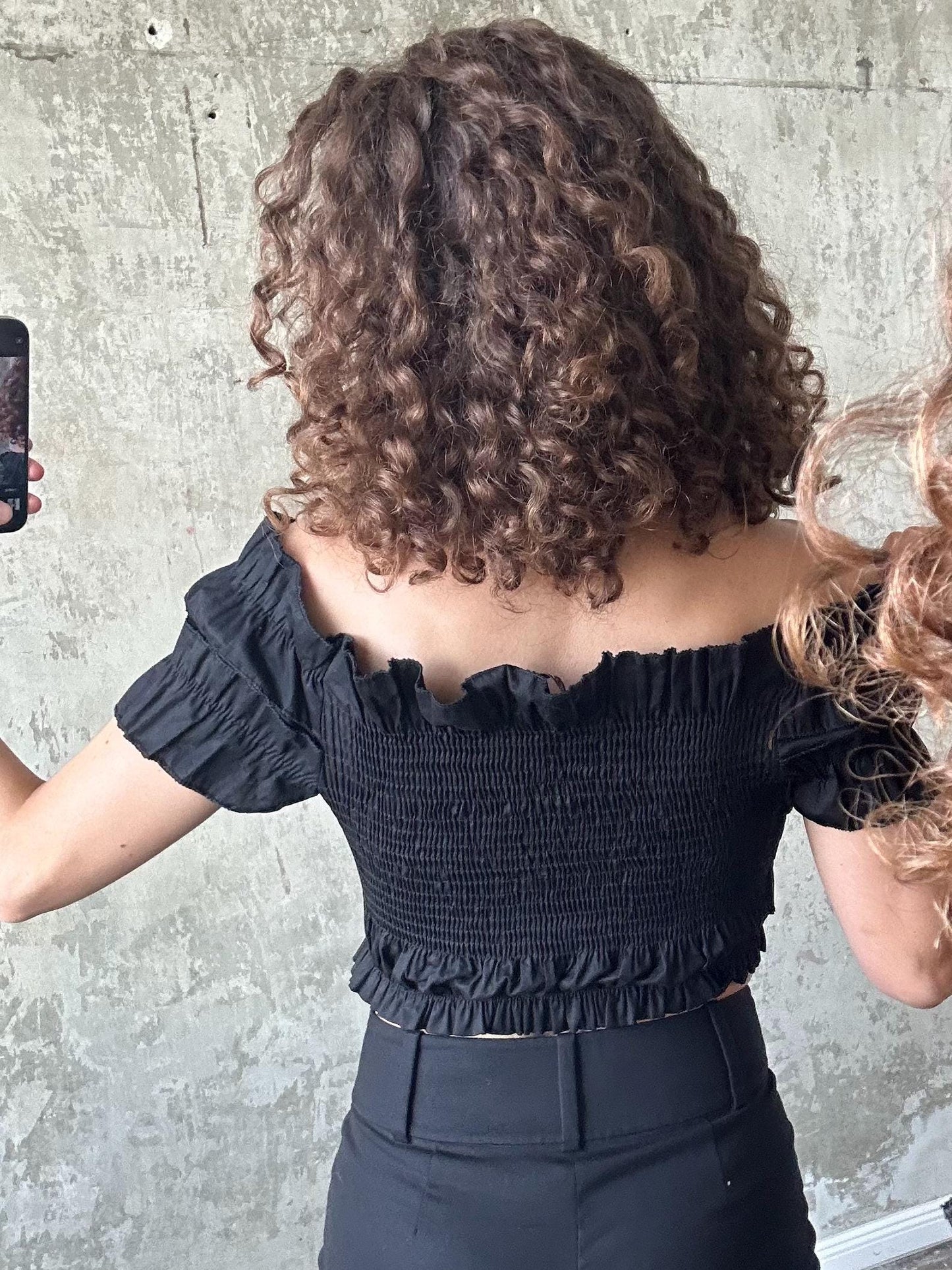 a person taking a selfie with a smartphone, capturing their back view.
