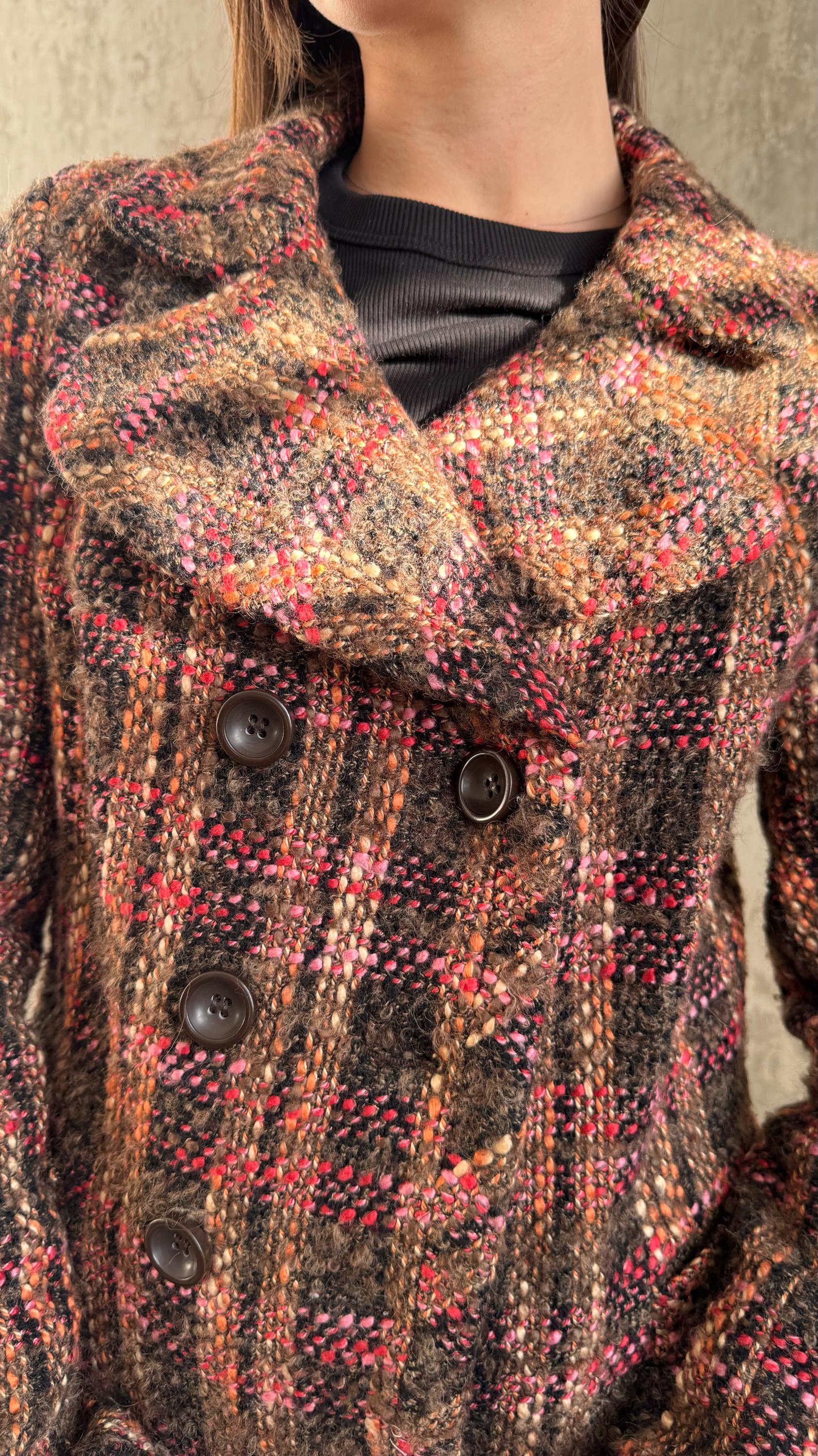 A close-up image of a woman wearing a brown plaid coat with three buttons.