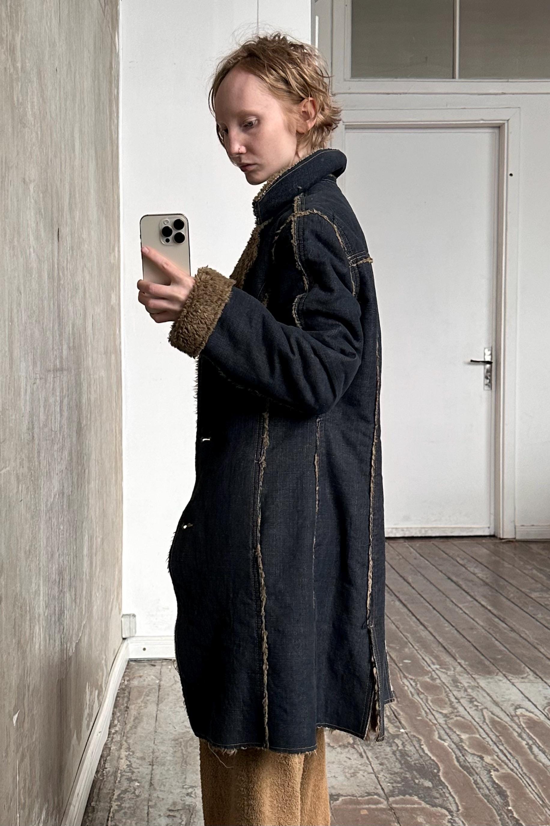a woman standing in a room holding a cell phone
