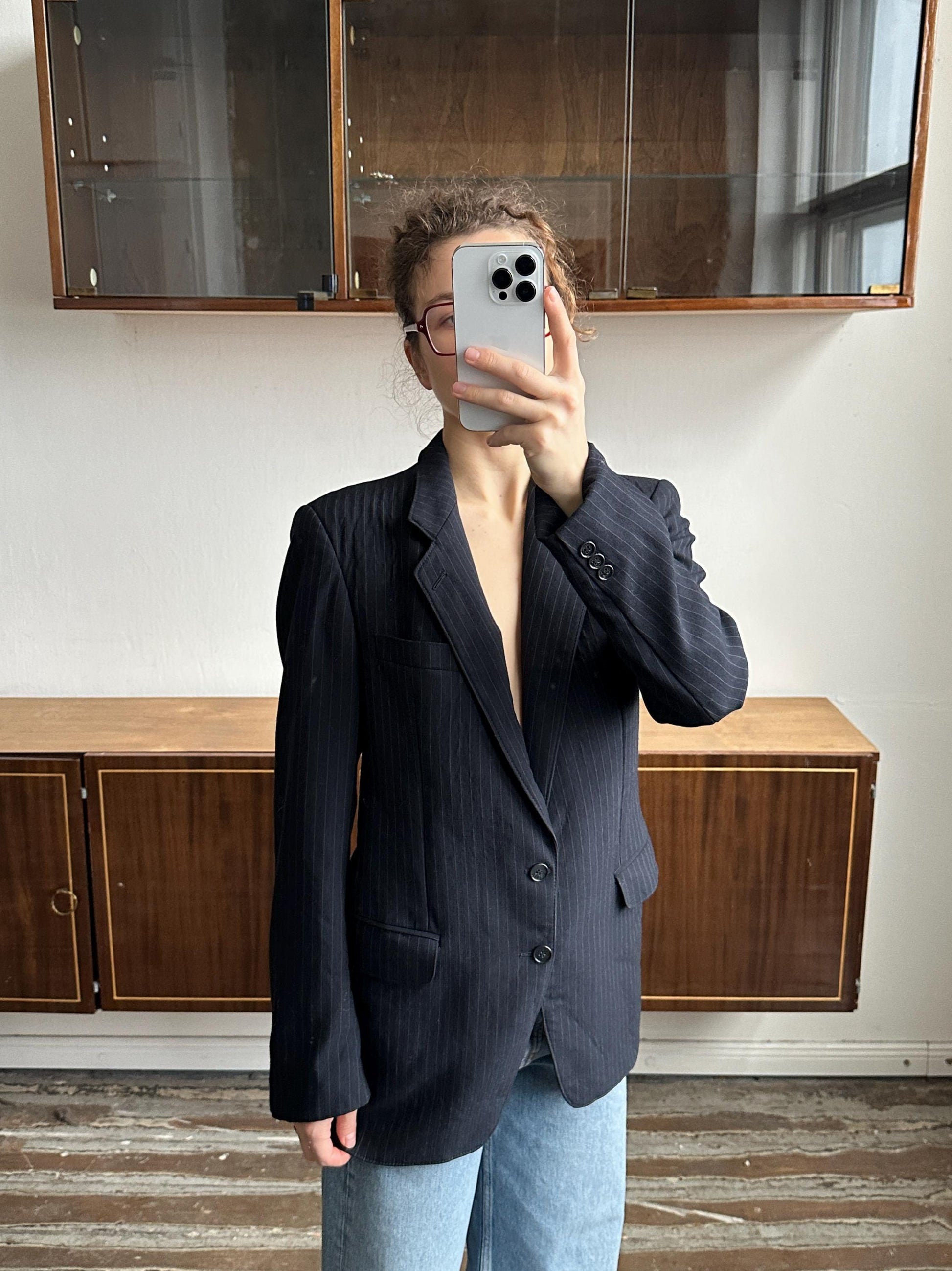 A person is taking a selfie with a smartphone, holding the phone up to their face in front of a wooden cabinet.