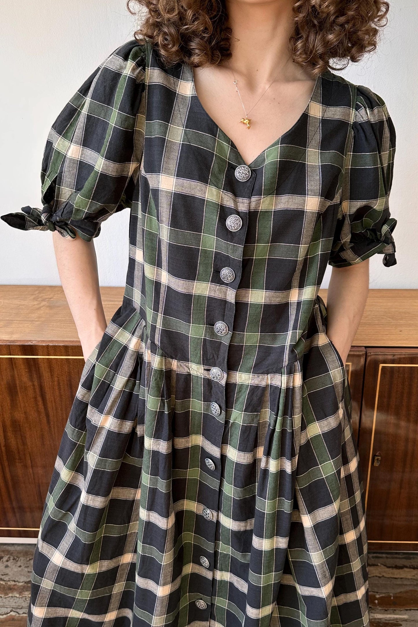 a woman wearing a green and black plaid dress