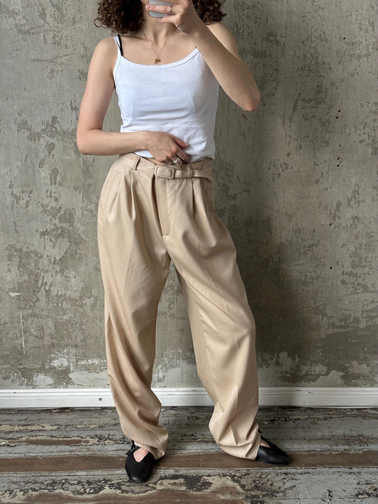 a woman in a white tank top and tan pants